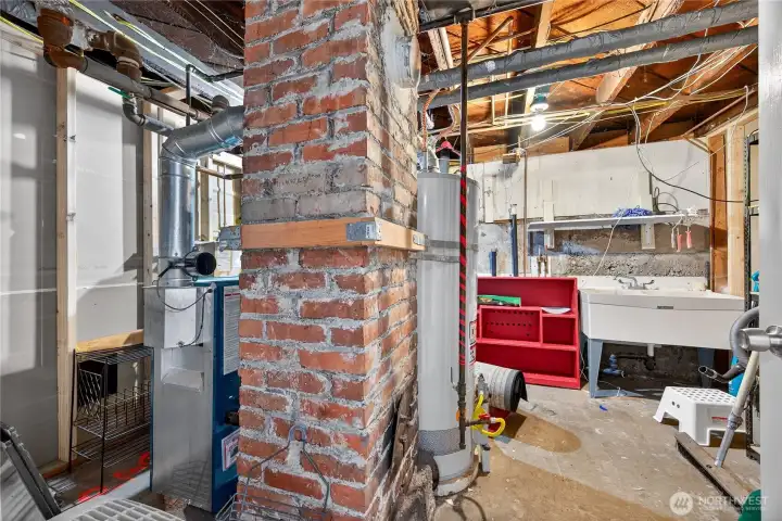 Basement utility room with hot water heating system, tool area, storage, and wash basin for practical use.