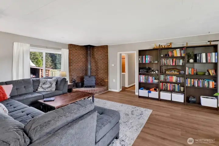 The well-appointed living room features a cozy wood stove, providing both charm and economical, efficient heating throughout the space.