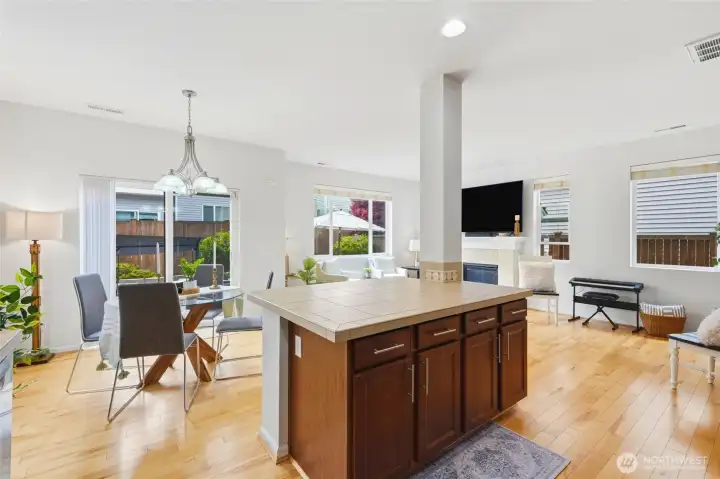 Open Living Space Inviting open floor plan connecting the kitchen, dining, and living areas, highlighted by hardwood floors, oversized windows, and a warm, welcoming atmosphere. Open Living Space Inviting open floor plan connecting the kitchen, dining, and living areas, highlighted by hardwood floors, oversized windows, and a warm, welcoming atmosphere.
