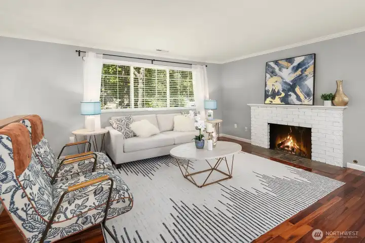 The bright and inviting living room features rich Brazilian Cherry hardwood floors, a classic fireplace, and abundant natural light streaming through large windows. The bright and inviting living room features rich Brazilian Cherry hardwood floors, a classic fireplace, and abundant natural light streaming through large windows.