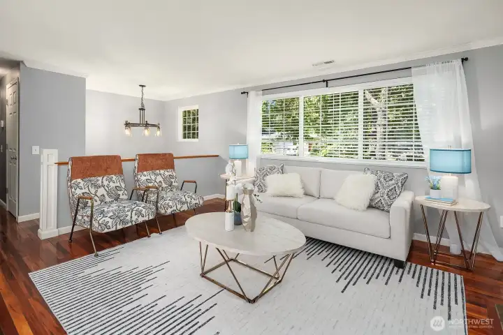 This wider angle of the living room showcases the open flow into the dining area, with gleaming hardwood floors and natural light creating a warm, connected living space. This wider angle of the living room showcases the open flow into the dining area, with gleaming hardwood floors and natural light creating a warm, connected living space.