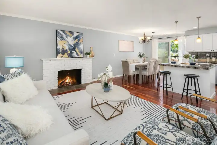 Another perspective of the living space highlights the cozy fireplace, elegant hardwood floors, and seamless connection to the dining area and updated kitchen beyond. Another perspective of the living space highlights the cozy fireplace, elegant hardwood floors, and seamless connection to the dining area and updated kitchen beyond.