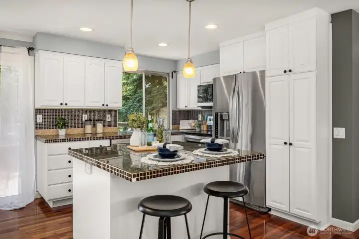 A closer look at the kitchen reveals sleek stainless steel appliances, a classic tile backsplash, and a generous island with bar seating perfect for casual dining or entertaining. A closer look at the kitchen reveals sleek stainless steel appliances, a classic tile backsplash, and a generous island with bar seating perfect for casual dining or entertaining.