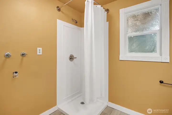 The three-quarter bath's walk-in shower offers a clean and functional layout with a bright window providing natural light and ventilation. The three-quarter bath's walk-in shower offers a clean and functional layout with a bright window providing natural light and ventilation.