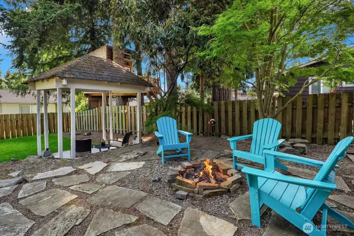 The flagstone fire pit area with bright Adirondack chairs offers a cozy and inviting outdoor gathering spot, rounding out the backyard's multiple entertaining zones perfectly. The flagstone fire pit area with bright Adirondack chairs offers a cozy and inviting outdoor gathering spot, rounding out the backyard's multiple entertaining zones perfectly.
