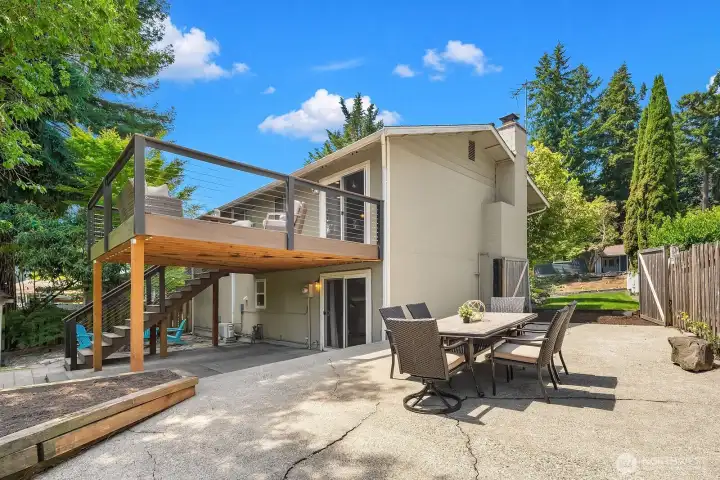 This exterior view showcases the impressive elevated deck, covered patio below, and alfresco dining area, illustrating the exceptional multi-level outdoor living this home provides. This exterior view showcases the impressive elevated deck, covered patio below, and alfresco dining area, illustrating the exceptional multi-level outdoor living this home provides.