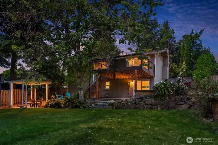 This breathtaking dusk shot of the home's rear exterior beautifully highlights the glowing deck, gazebo, and lush landscaping, perfectly capturing the warmth and charm of this exceptional outdoor living space. This breathtaking dusk shot of the home's rear exterior beautifully highlights the glowing deck, gazebo, and lush landscaping, perfectly capturing the warmth and charm of this exceptional outdoor living space.