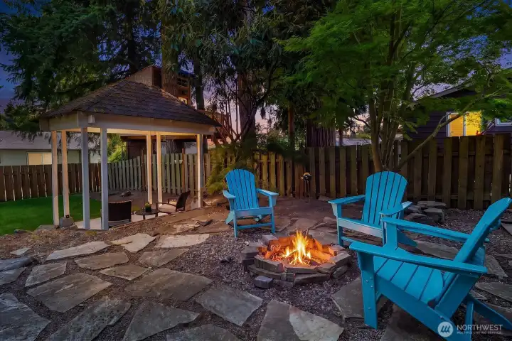 A magical twilight view of the flagstone fire pit and Adirondack chairs, with the gazebo glowing softly in the background, perfectly showcasing this backyard's enchanting evening ambiance. A magical twilight view of the flagstone fire pit and Adirondack chairs, with the gazebo glowing softly in the background, perfectly showcasing this backyard's enchanting evening ambiance.