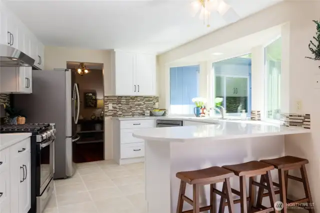 Crisp white soft-close cabinetry offers ample storage while lending a clean, modern look. Gleaming quartz countertops provide plenty of workspace and an elegant finish, perfect for meal prep or casual dining. Pull up to the eating bar and visit while the chef is in the kitchen or to grab a informal bite to eat.