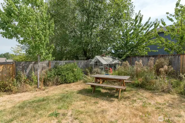 Spacious yard with nice deck, mature landscaping, garden area and greenhouse.