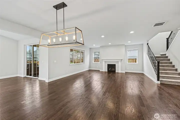 The open living room features a cozy gas fireplace, expansive windows, recessed lighting, and convenient access to the upstairs, blending style and functionality seamlessly.