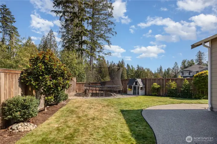 This expansive space features a covered patio with recessed lighting, fire pit, grassy area, shed, sprinkler system, and dedicated garden area.