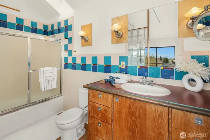 Primary suite bathroom with warmth, character and bright tiles.