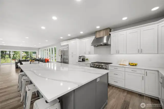 Step into a gourmet chef's haven featuring premium GE Monogram appliances, complemented by an oversized quartz island that offers both casual dining space and abundant storage.