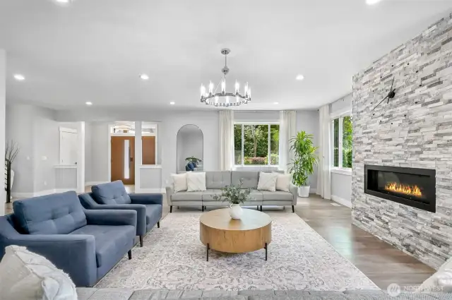 The elegant living room features a inset fireplace on a custom rock wall and a centerpiece chandlier.