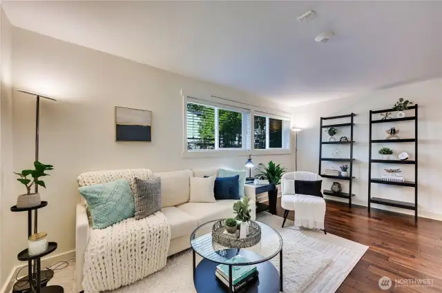 Large living room featuring real hardwood floors and recent fresh white paint.