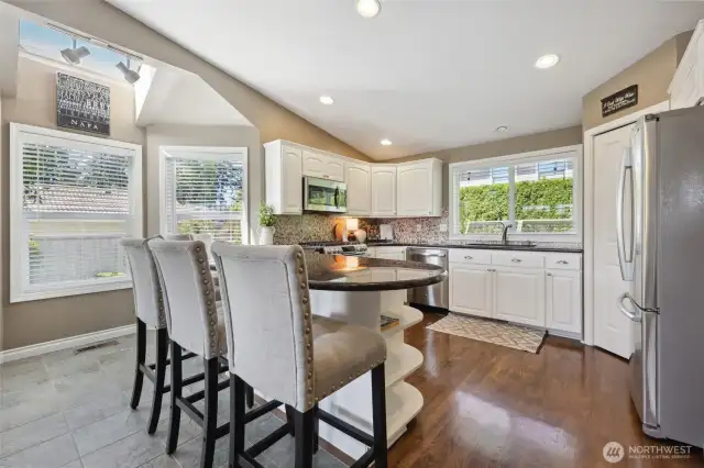 Kitchen is open and bright with hardwood floors, granite countertops, a peninsula and stainless steel appliances. Also seen here is a corner pantry adding plenty of storage space.