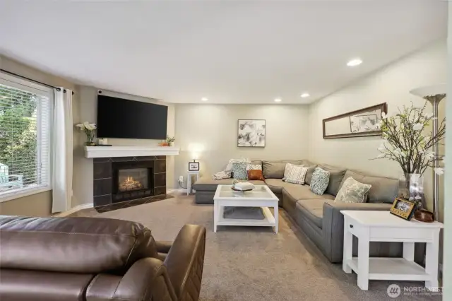 View of living room from kitchen. Room for a sizable sectional. Keep warm in the cooler month by cozying up by your gas fireplace.