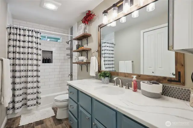 Upstairs full bath with custom tile, Schluter shower water proofing system, custom painted cabinetry, new lights and fixtures and Quartz countertops. Seen in the mirror is a nice sized linen closet.