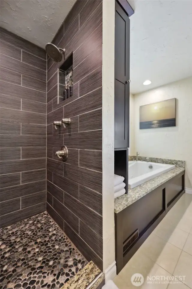This walk in shower has a rain shower head, a separate shower wand, & pebble tile that feel amazing on your feet!