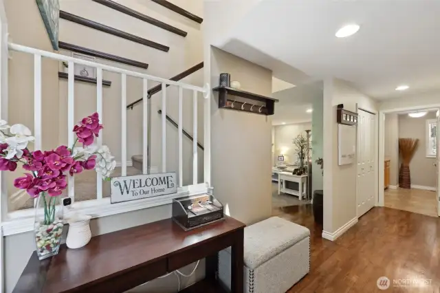 Main entry foyer with soaring ceilings, chandelier and hardwood floors. Also seen here is a wall of custom shelves that adorn the stairway. Nice sized coat closet just off the entrance.
