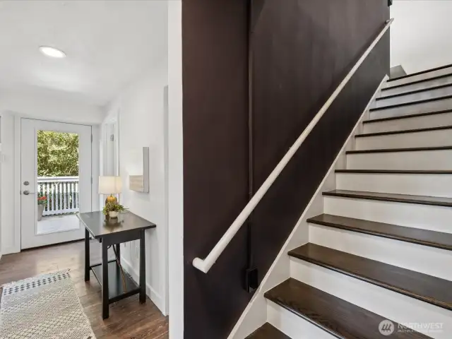 Bottom of stairs to lower floor, door at end of hallway exists to lower deck