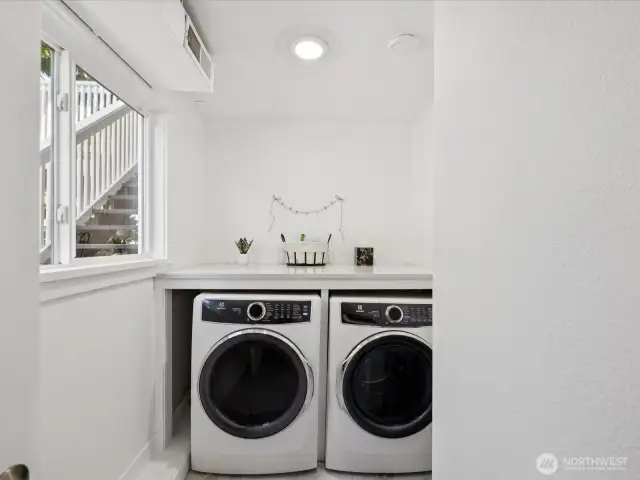 Gorgeous dedicated laundry room complete with folding shelf, Electrolux washer & dryer, room is full of natural light