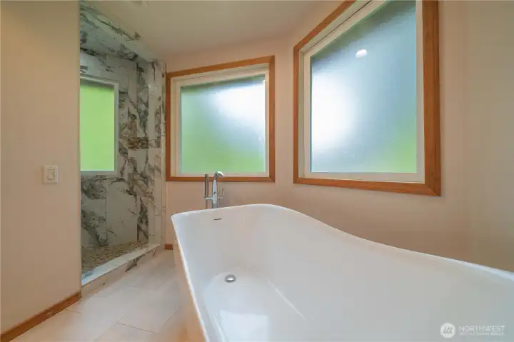 Luxurious primary bathroom with standalone tub and shower with rain head and more.