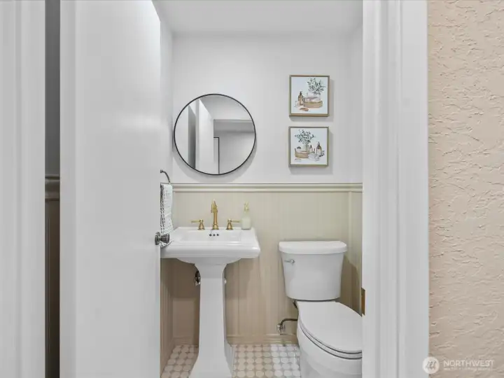 Updated main floor powder room with pedestal sink, modern fixtures, and classic wainscoting detail.