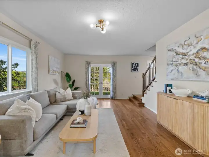Spacious living area with large windows and French doors leading outside, offering natural light and easy indoor-outdoor flow.