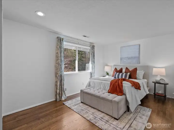 Bedroom featuring hardwood floors, natural light, and a clean, calming design.