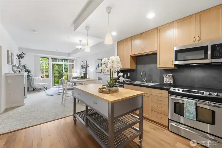 Expanded kitchen view highlighting the island, stainless appliances, and the open connection to the dining and living spaces