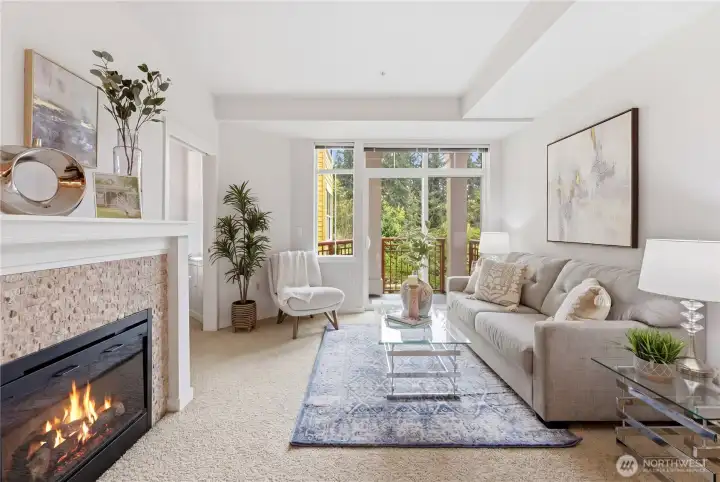 Spacious living room with a fireplace, modern finishes, and expansive windows that bring in natural light and views of the greenery outside.