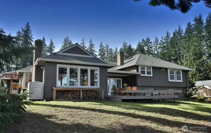 North side of home. The four windows here are to one of your two living rooms. Expansive deck has French doors with access from both living rooms. Ample supply of wood for your wood fireplace. Roof replaced in 2018. North side of home. The four windows here are to one of your two living rooms. Expansive deck has French doors with access from both living rooms. Ample supply of wood for your wood fireplace. Roof replaced in 2018.