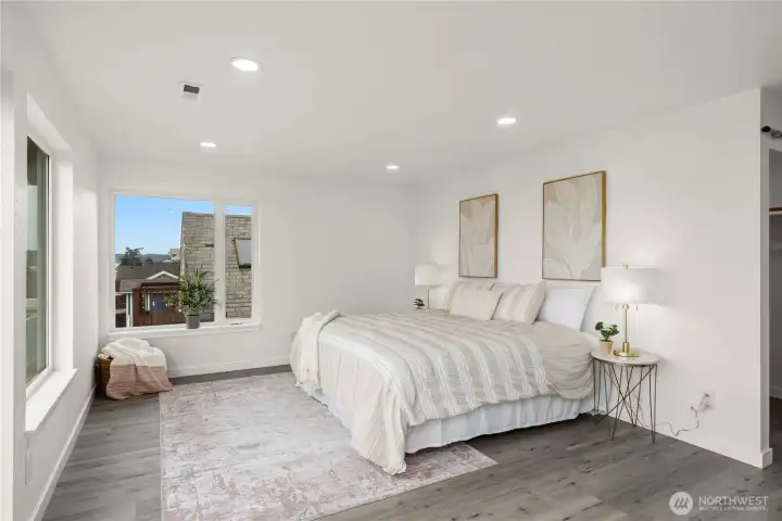 Serene primary retreat showcases breathtaking Puget Sound views and a large walk-in closet extending across the entire wall behind the bed.