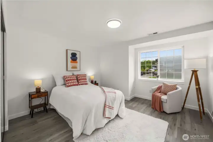 Bright upstairs bedroom featuring updated flooring, fresh paint, and a large picture window that fills the space with natural light.