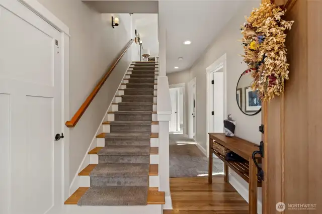 Front entry. Elevator to the left, and guest bed, bath/laundry, and primary suite to the right. Stairs lead to living, dining, and kitchen.