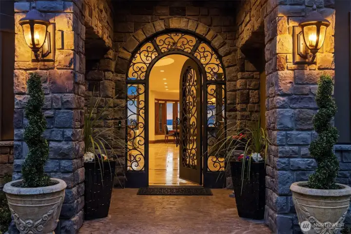 The mansion's front entrance stands as a dramatic focal point with a sweeping archway with scrolling wrought iron detail.