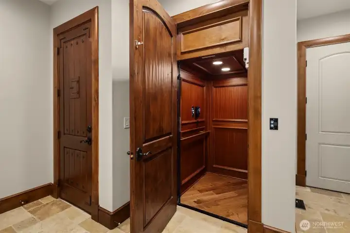 A private elevator is a seamless extension of this estate wrapped in the continued rich grained Sapele wood paneling.