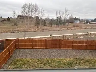 Fully fenced back yard has gate to front of house by driveway.