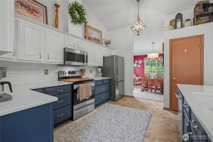 Kitchen view one, towards your formal dining room. AMAZING remodeled chef's kitchen, with soaring ceilings, gorgeous quartz countertops and look at those cabinets! Beautiful. Your pantry is the door to the right.