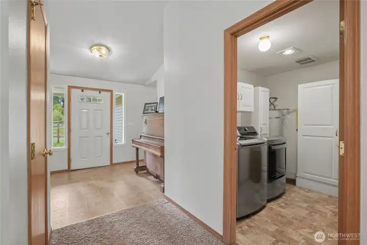 View down the hallway from your kitchen to entry, coat closet to left. On your right is a nicely-sized utility room with included newer washer & dryer plus cabinetry!