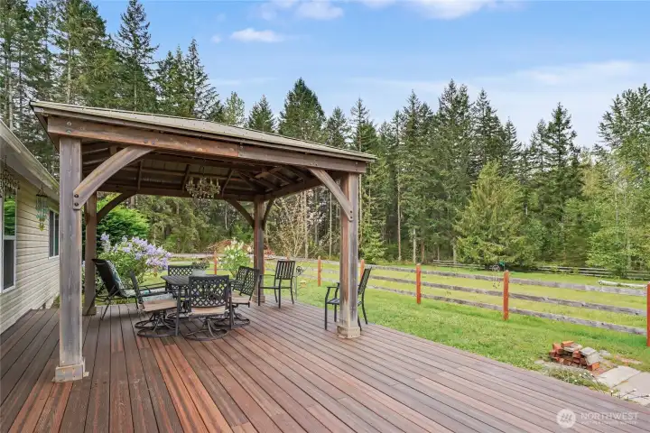 View of your trex-like deck from the patio doors off of your kitchen, this deck is MASSIVE, and the Costco Pergola stays! Sit and relax and watch your horses in one of the pastures.
