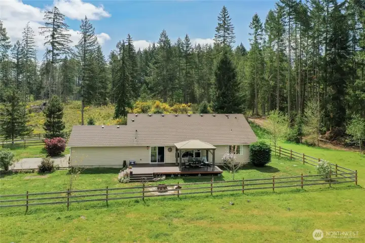 Drone view of the back of the house, I love that there are tall trees all around this property but not near the home! Easy care for moss & no pine needles.