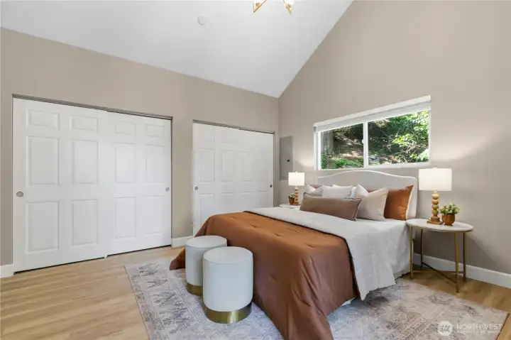 Primary bedroom retreat featuring dual closets, a private deck, and vaulted ceilings, and a bright, airy atmosphere.