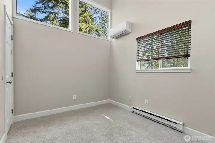Bright and airy second bedroom on the upper-level featuring oversized windows, updated finishes, and a comfortable, versatile layout.