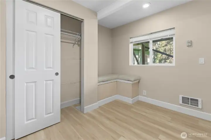 Cozy lower-level room with built-in bench seating and closet storage, ideal for guests, reading, or creative use.