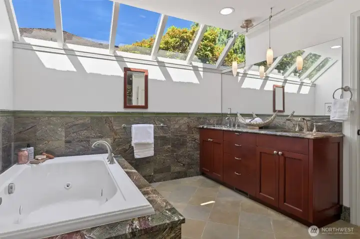 Spa-inspired primary bath with heated floors, jetted tub, jetted shower, and skylights.