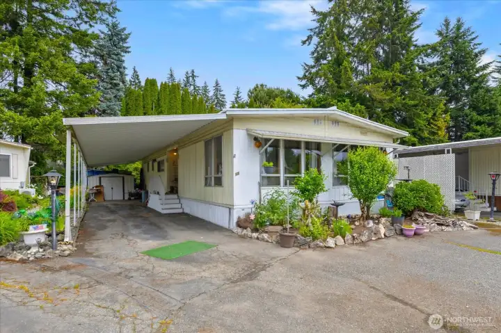 Deep covered carport featuring a convenient attached storage shed.