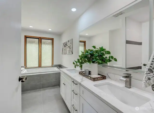 Beautifully remodeled bath with dual sink granite top vanity and sunken tub and heated tile floor.